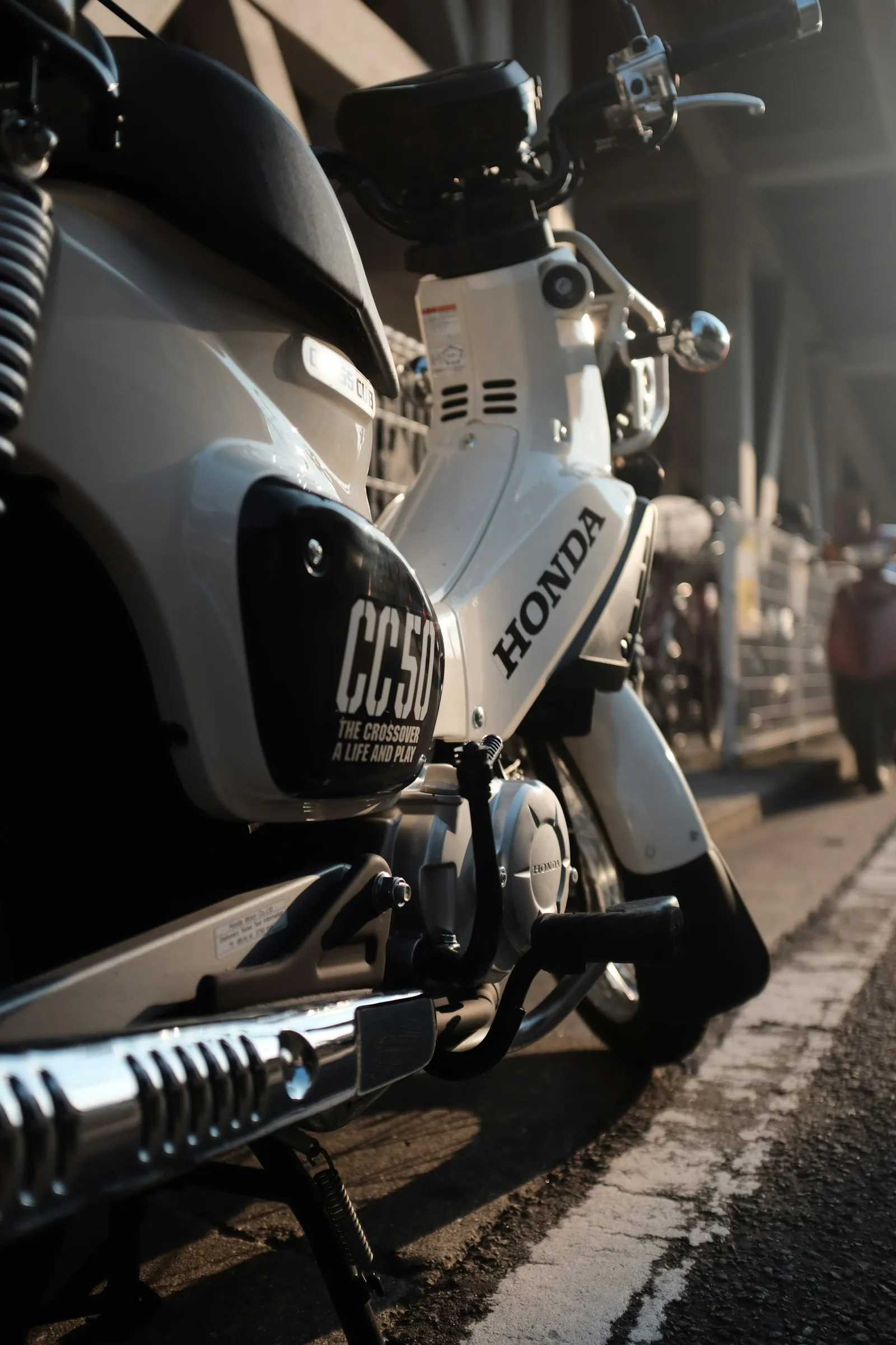 Close-up of a white Honda Cross Cub with a CC50 badge and exhaust guard