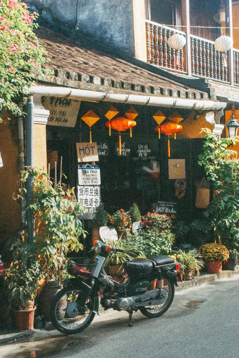 A small motorcycle outside a lantern-lit restaurant. Contemporary photograph by Huỳnh Tấn Hậu.